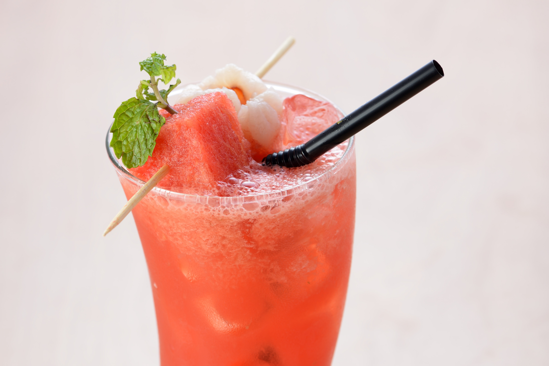 Lychee watermelon cocktail in a glass with fresh mint, lychee, and watermelon garnish made with Yeo's Lychee Drink