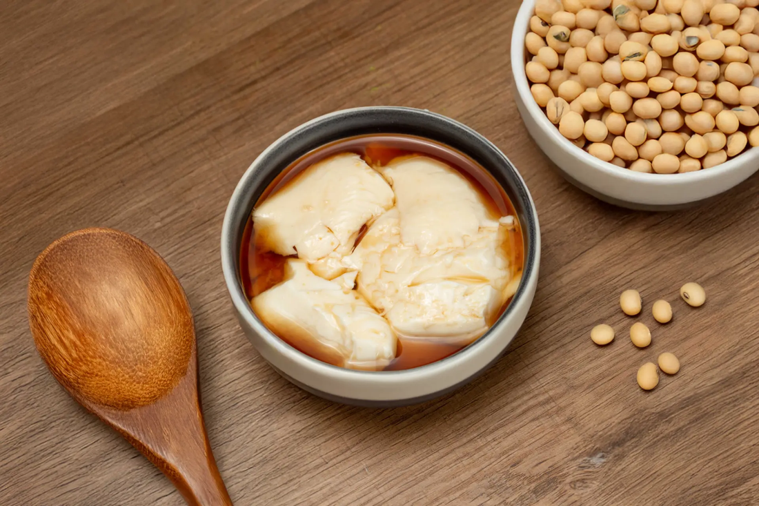Homemade soy bean pudding in a bowl topped with warm ginger syrup made with Yeo's Soy Drink