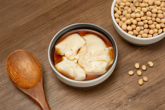 Homemade soy bean pudding in a bowl topped with warm ginger syrup made with Yeo's Soy Drink